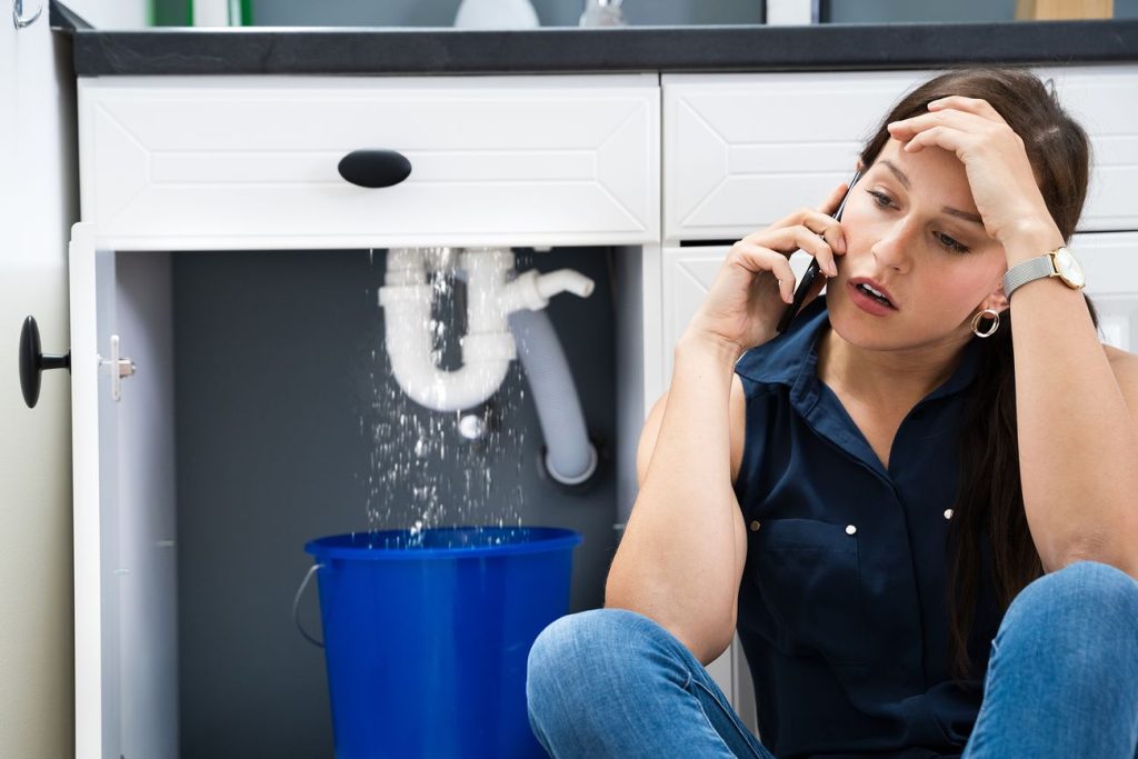 A person speaking with a plumber on the phone, discussing a plumbing issue