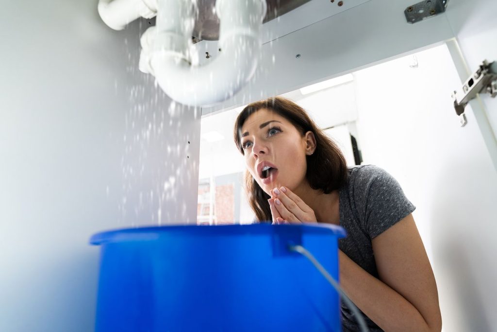 Under-sink pipe leaking water into a bucket placed on the floor